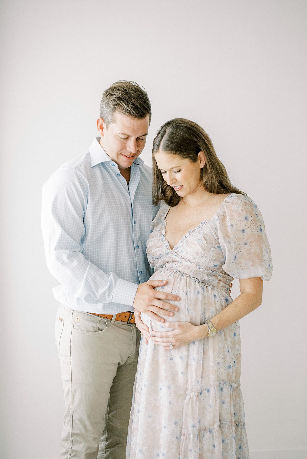 expecting parents holding and looking at pregnant baby bump by memphis maternity photographer