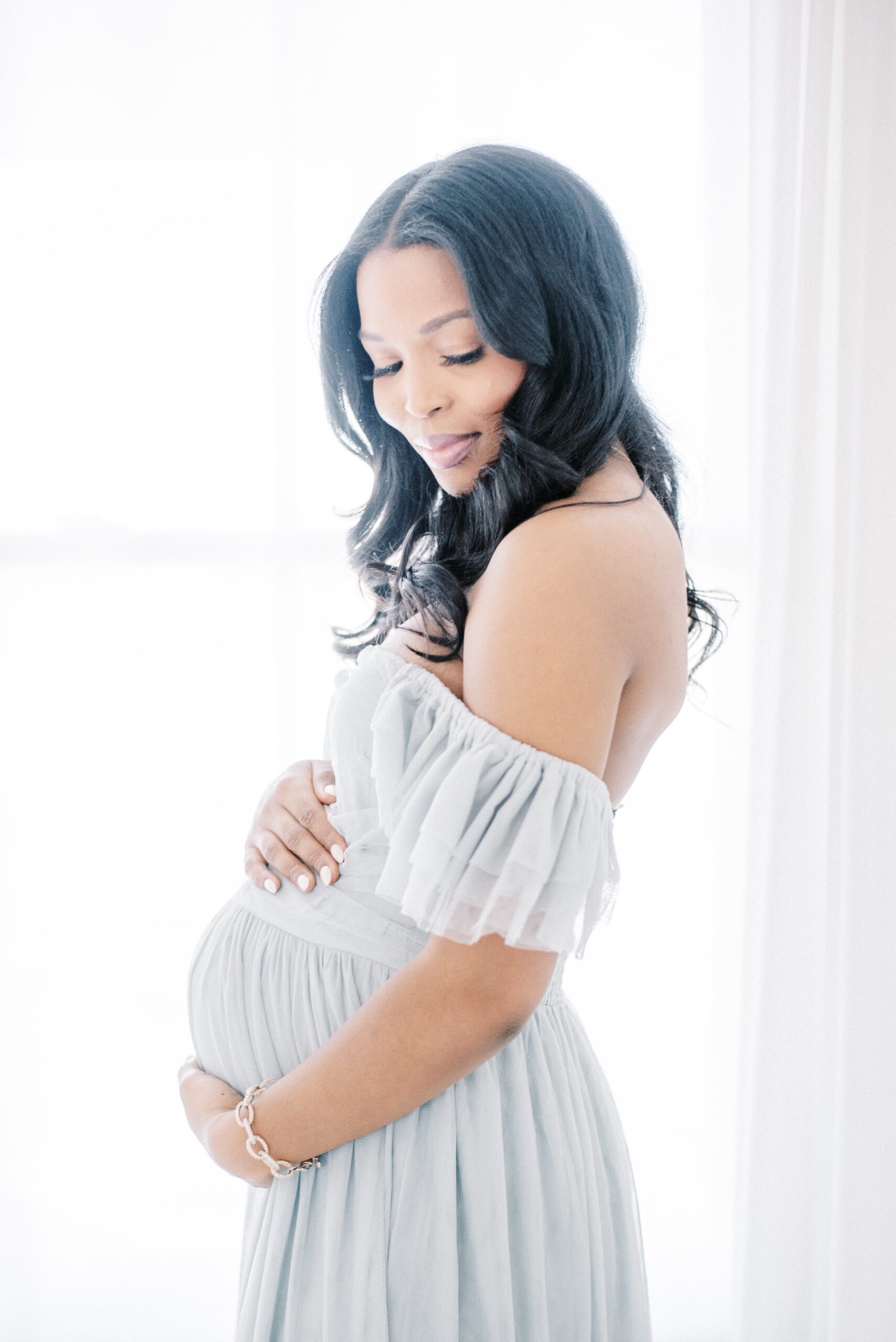 pregnant woman cradling baby bump in maternity photo